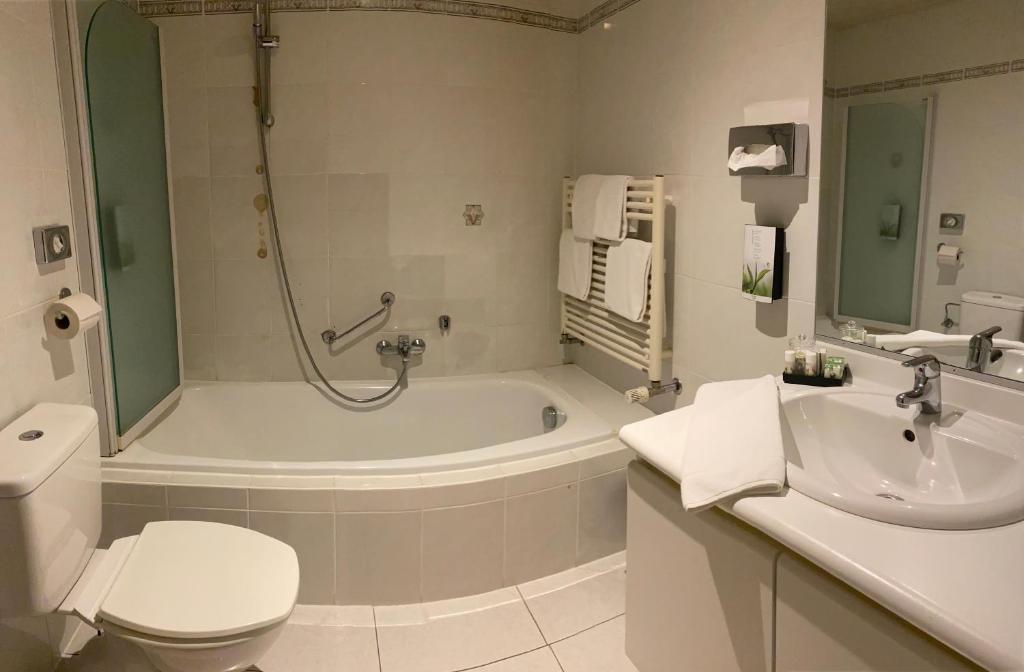 a bathroom with a tub and a toilet and a sink at HOTEL BORNEM in Bornem