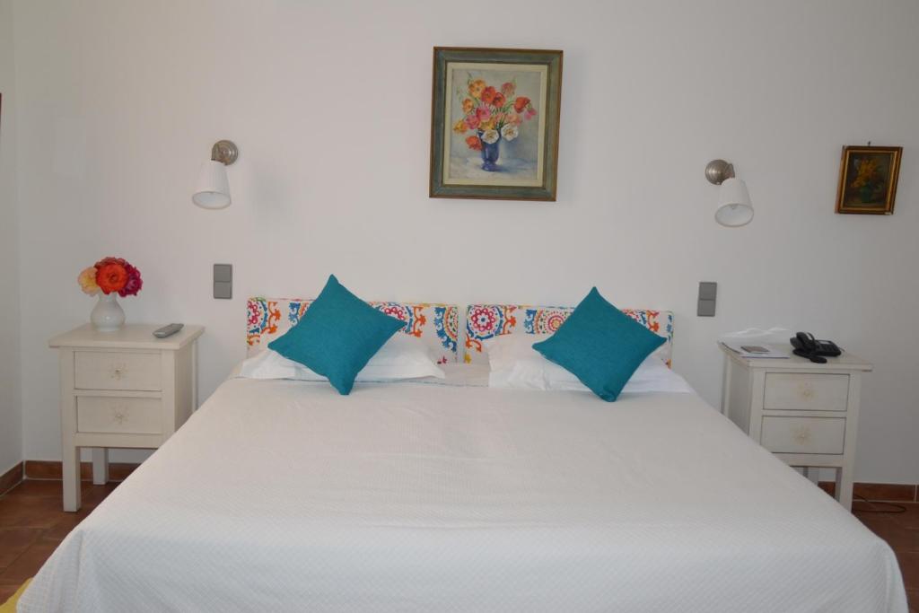 a bedroom with a large white bed with blue pillows at La Ferme D'Augustin in Saint-Tropez