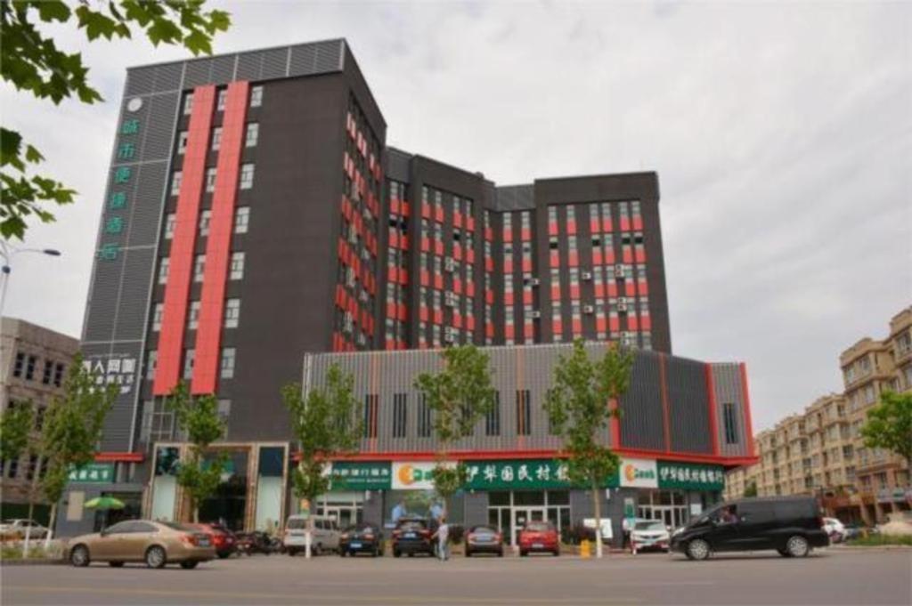 un gran edificio con coches estacionados en un estacionamiento en City Comfort Inn Yi'Ning Jichang Road Shanghaicheng, en Kipekyüzi