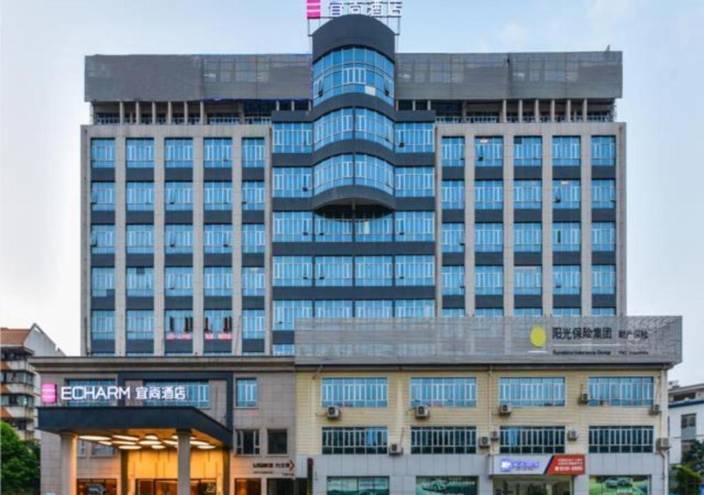 un grand bâtiment avec des fenêtres bleues dans une ville dans l'établissement Echarm Hotel Nanning Baisha Avenue Shizhuling Metro Station, à Nanning