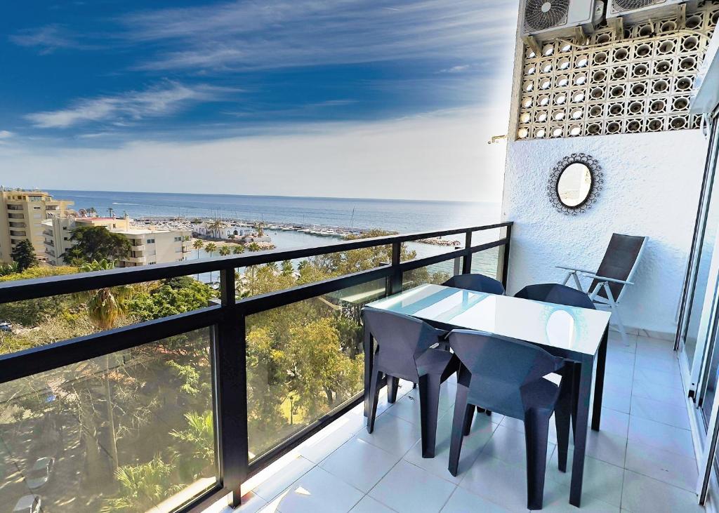 マルベーリャにあるSkol 727 Lovely 2 Bedroom Duplex in Marbella Centerの海を望むバルコニー(テーブル、椅子付)