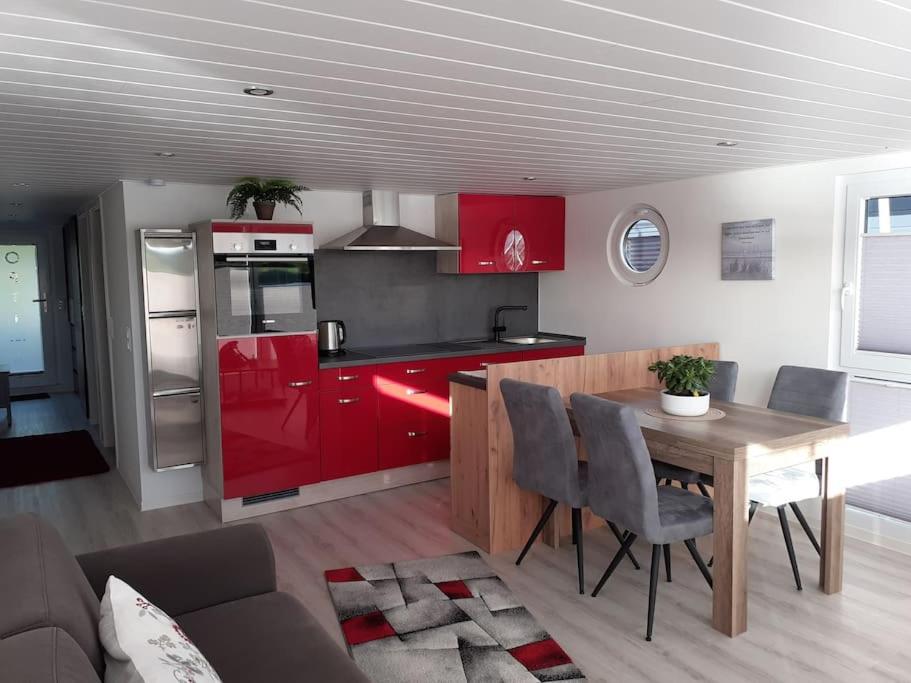 a kitchen with red cabinets and a table with chairs at Hausboot Optima in Wangerland