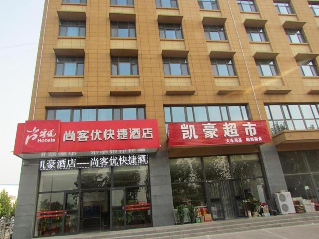 een gebouw met rode borden aan de voorkant bij Thank Inn Hotel Hebei Xingtai Shaheweisan Road Expressway Intersection in Shahecheng