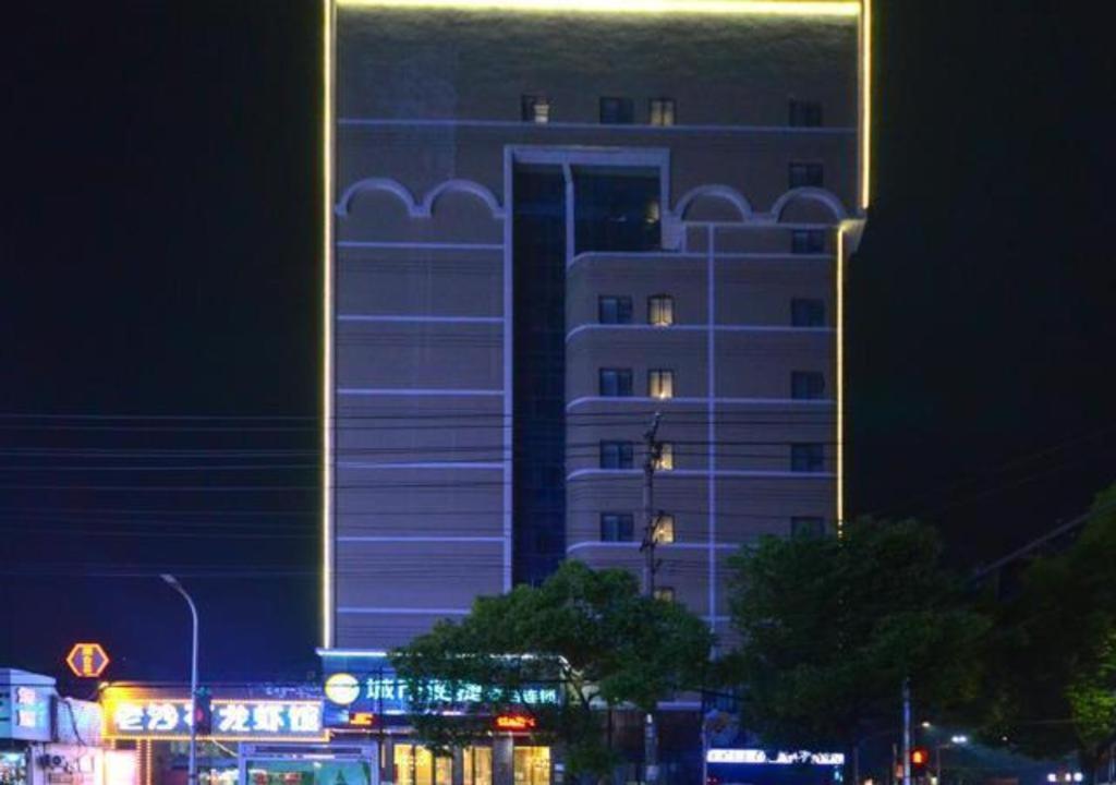 Un grand bâtiment blanc avec des lumières allumées la nuit dans l'établissement City Comfort Inn Jingzhou Hongxing Road Food Street, à Pu-ho