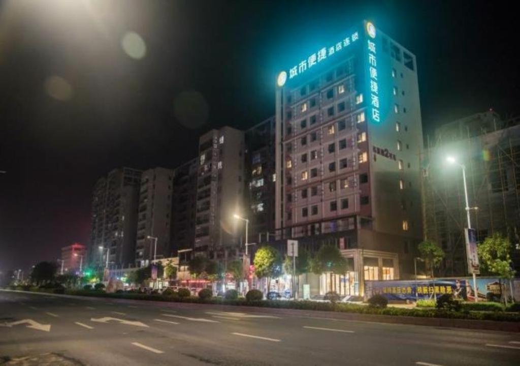 eine Stadtstraße in der Nacht mit einem großen Gebäude in der Unterkunft City Comfort Inn Wuzhou Municipal Government Vocational College in Wuzhou