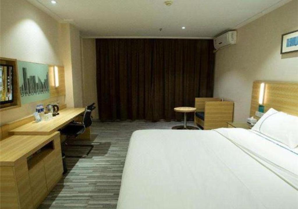 a hotel room with a large bed and a desk at City Comfort Inn Huangshi Daye Tongluowan Business Street in Daye