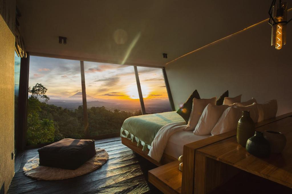 een slaapkamer met een bed en uitzicht op de zonsondergang bij Aurora Cabins by Panoramika in Jatiluwih