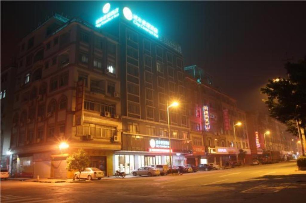 eine Straße in der Nacht mit Autos vor einem Gebäude in der Unterkunft City Comfort Inn Wuzhou South High Speed Railway Station in Cangwu