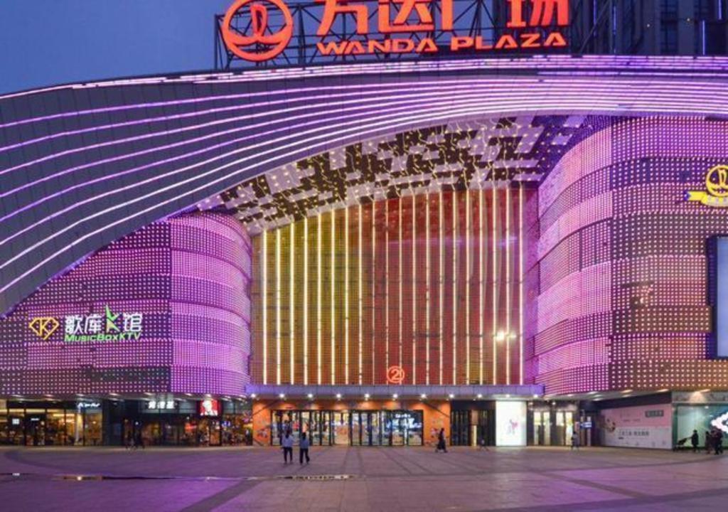 um grande edifício é iluminado em roxo em City Comfort Inn Jingzhou Wanda Plaza em Caoshi