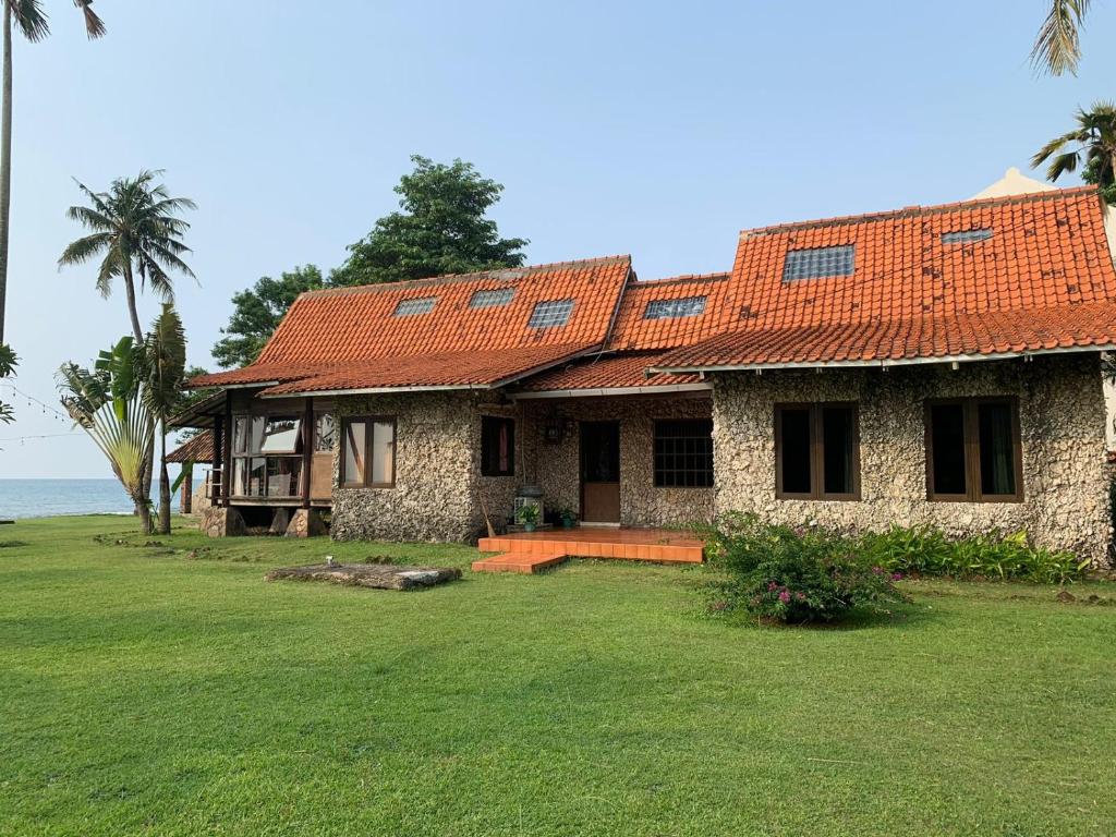 a stone house with an orange roof and a yard at Taverno Villa in Serang