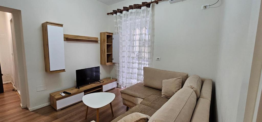 een woonkamer met een bank en een tv bij Ajla Komuna Apartament in Tirana