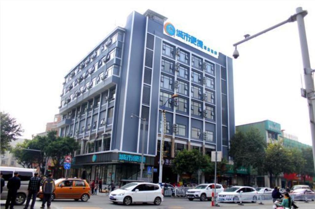 a large blue building with cars parked in front of it at City Comfort Inn Liuzhou Intime City Ma'anshan Music Fountain River View in Liuzhou
