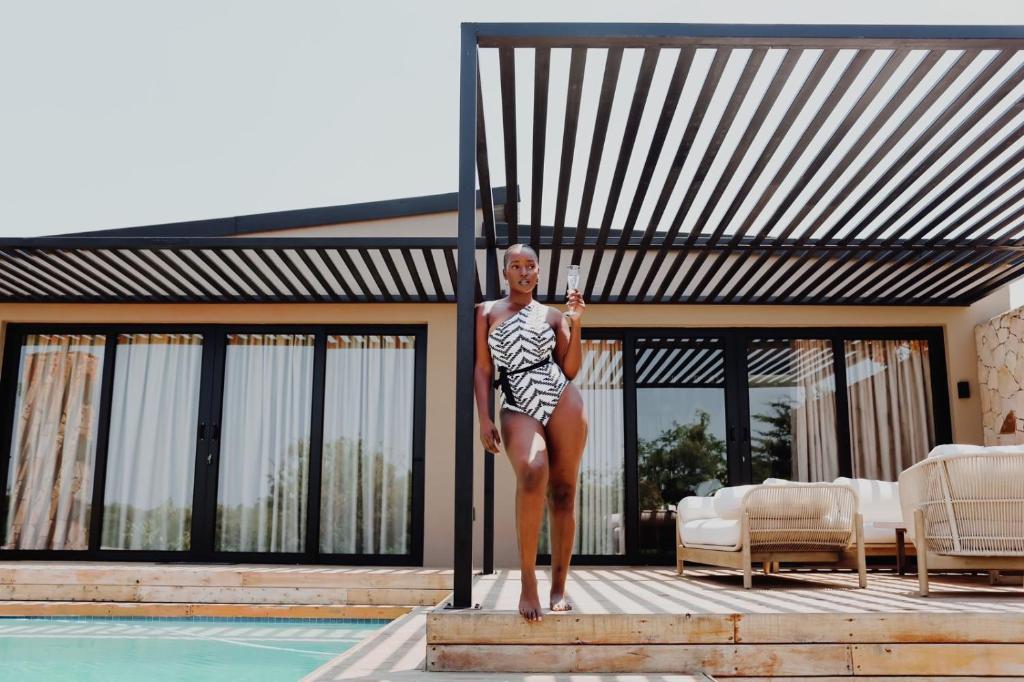 a woman in a bathing suit standing next to a swimming pool at Lira Boutique Lodge in Thohoyandou