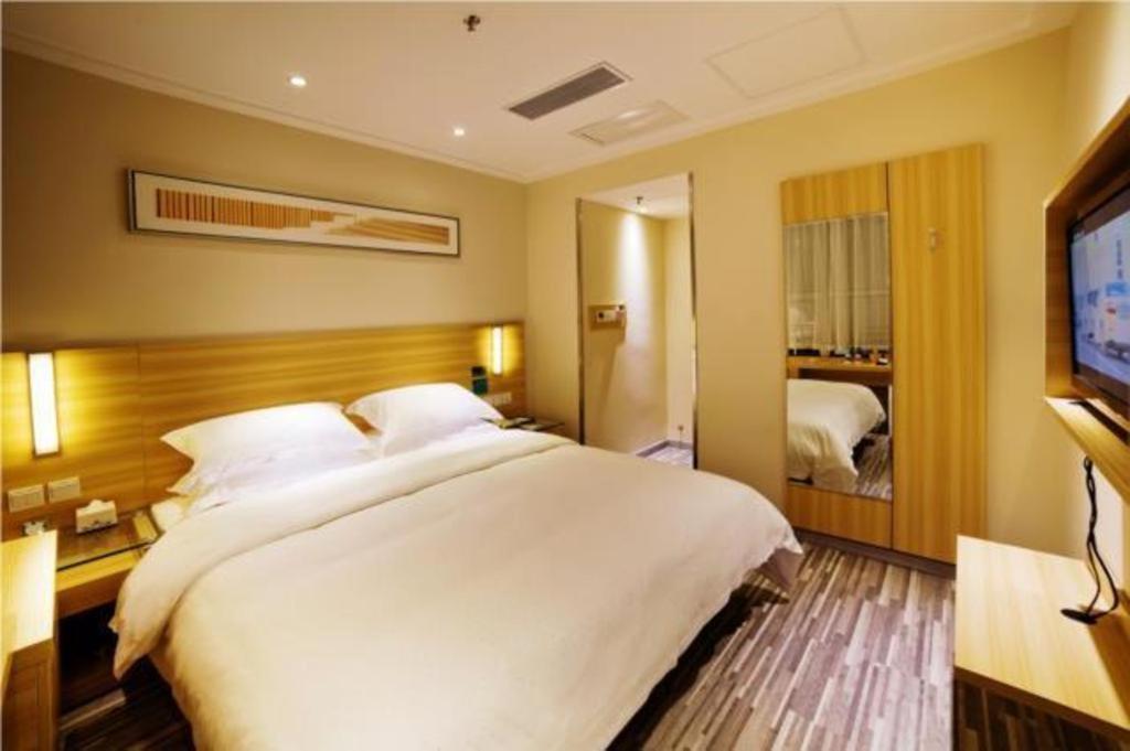 a bedroom with a large white bed and a television at City Comfort Inn Yichang East Station Rose Garden Global Harbor in Baiyang