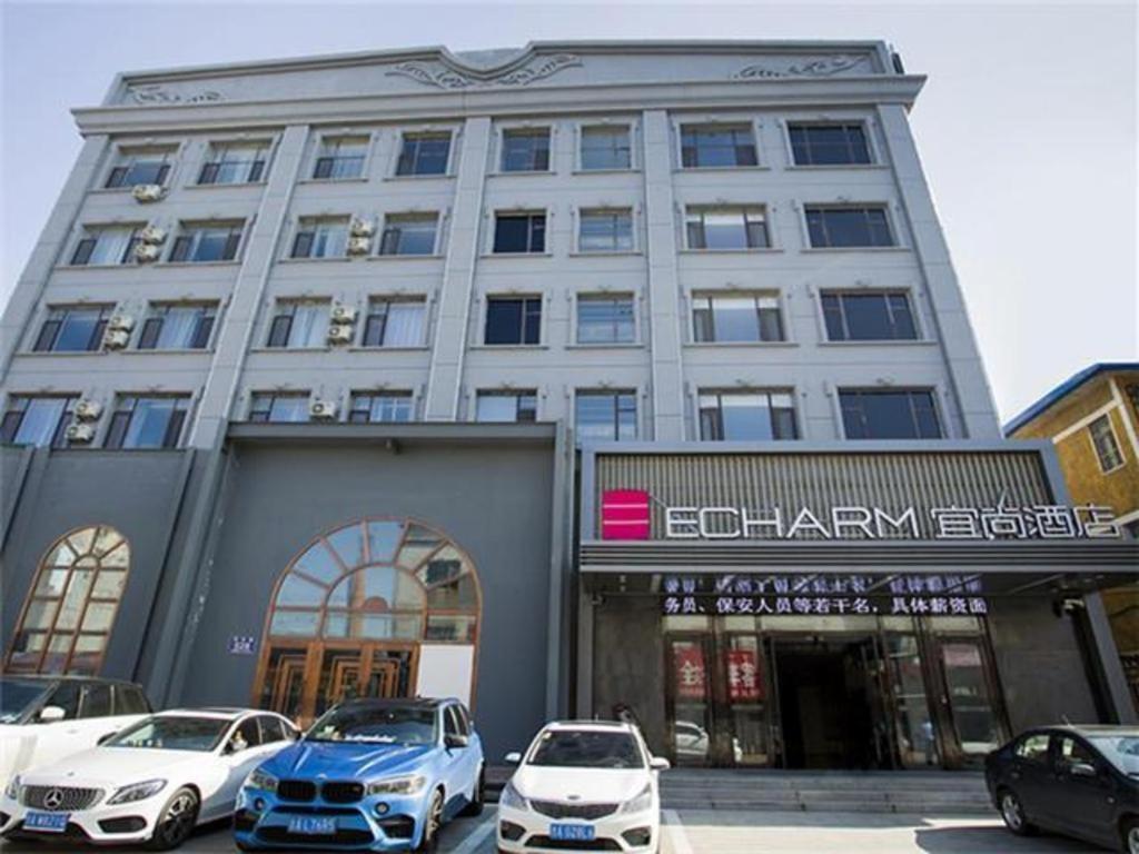 duży budynek z samochodami zaparkowanymi przed nim w obiekcie Echarm Hotel Changchun Jiutai District Government Railway Station 