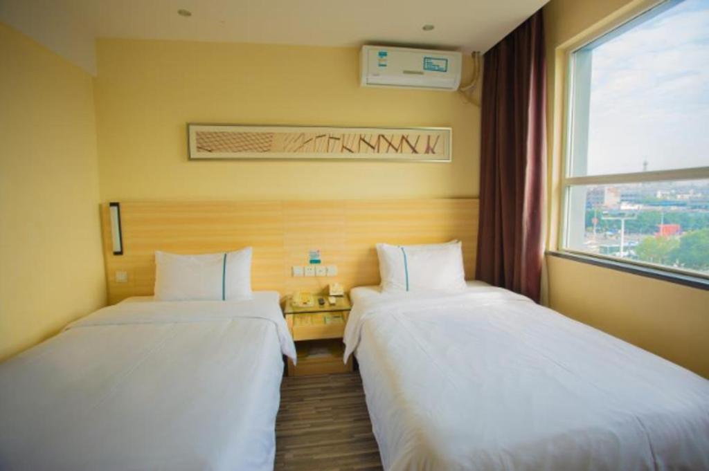 two beds in a room with a window at City Comfort Inn Ganzhou Railway Station in Ganzhou