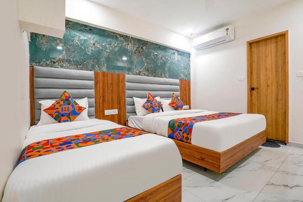 two beds in a room with white walls at FabHotel Amantra in Ahmedabad