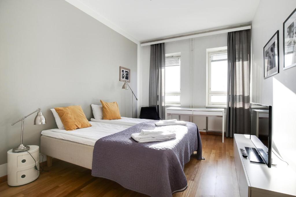 um quarto branco com uma cama com um cobertor azul em Kotimaailma Apartments Kamppi - 2BR in the city center with code lock em Helsinque