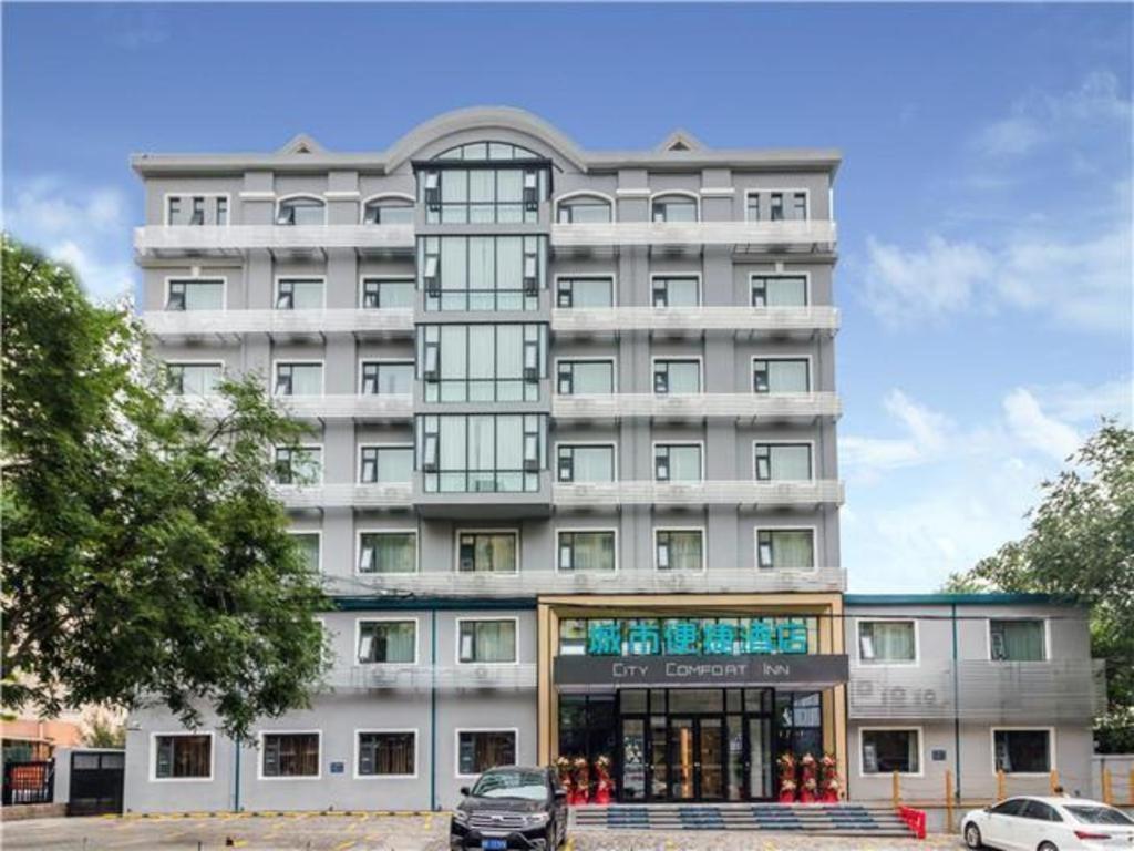 duży biały budynek z samochodem zaparkowanym przed nim w obiekcie City Comfort Inn Qingdao Taidong Business District w mieście Fushansuo