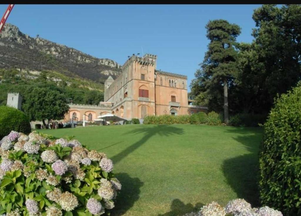 ein großes Gebäude mit einem grünen Garten mit Blumen in der Unterkunft Al castello da Nancy e il piccolo principe in Piano di Sorrento