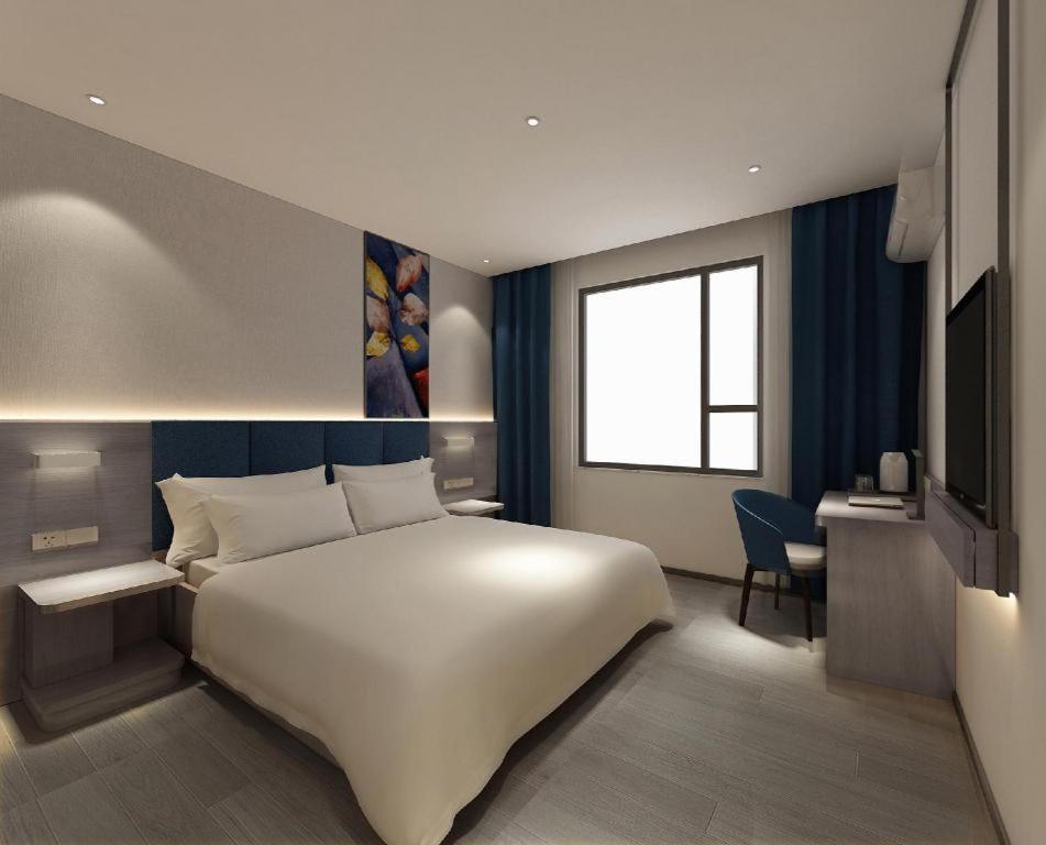 a bedroom with a large white bed and a television at 7 Days Premium Xianning Wenquan Shopping Center in Guanbuqiao