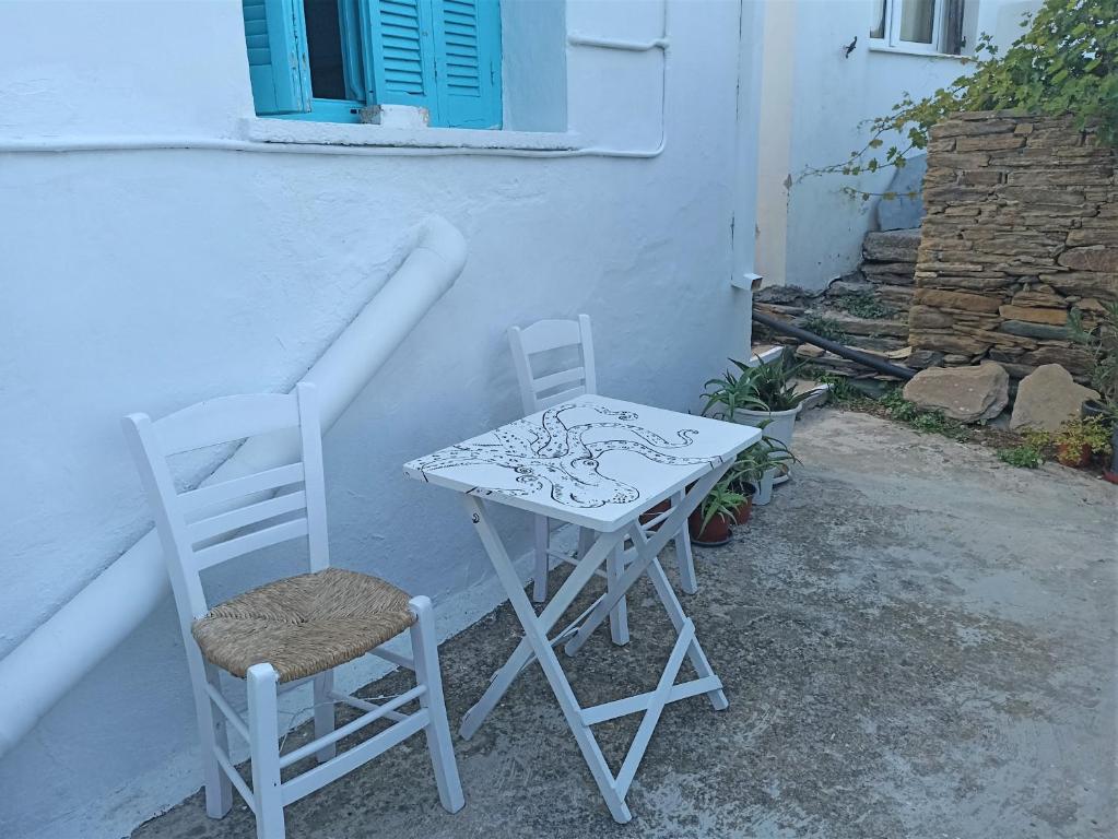 une table blanche et deux chaises à côté d'un bâtiment dans l'établissement La maison du Pêcheur, à Kourélion