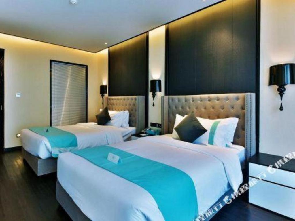 Dos camas en una habitación de hotel con dos en Xana Hotelle Luzhou High-Speed Railway Station Trading Market Passenger Terminal en Luzhou