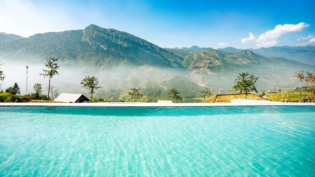 a swimming pool with mountains in the background at Supan Ecolodge in Sapa