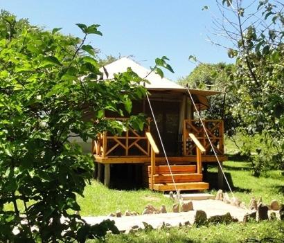 a small cabin with a porch and stairs to it at Ol Moran Tented Camp in Ololaimutiek