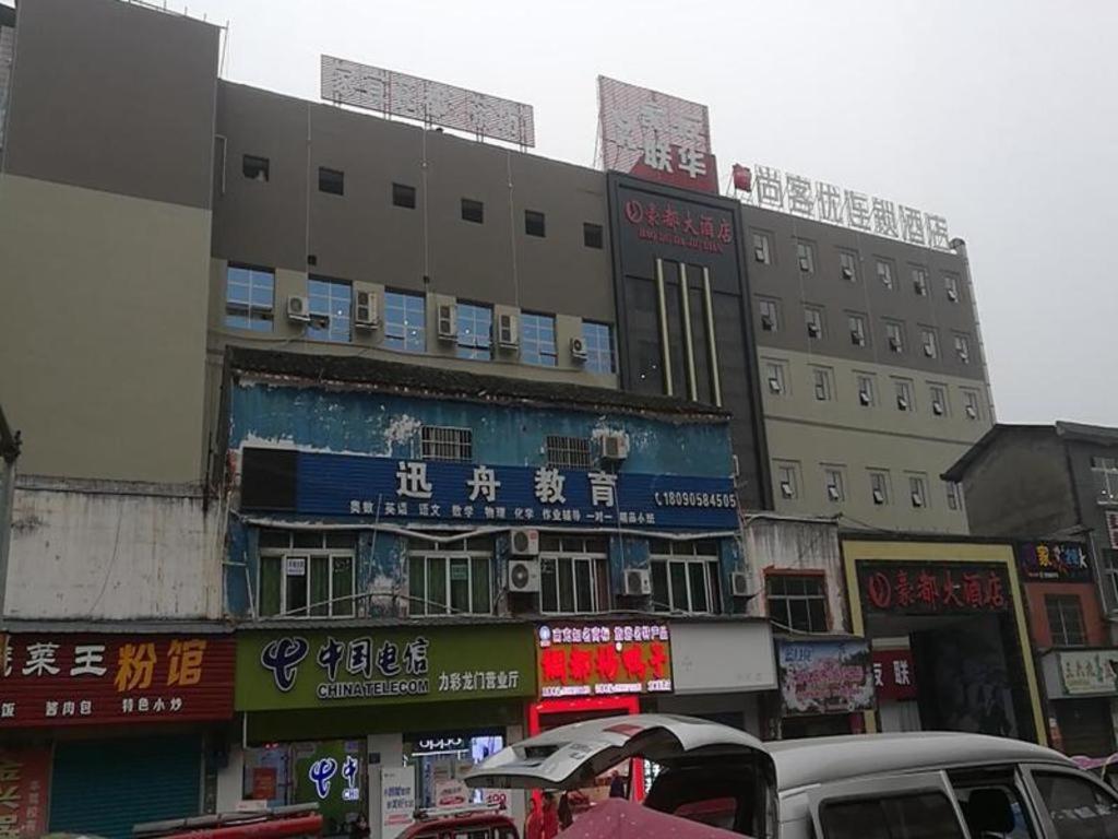 eine belebte Stadtstraße mit einem Gebäude mit Schildern in der Unterkunft Thank Inn Hotel Sichuan Nanchong Gaoping District Longmen 