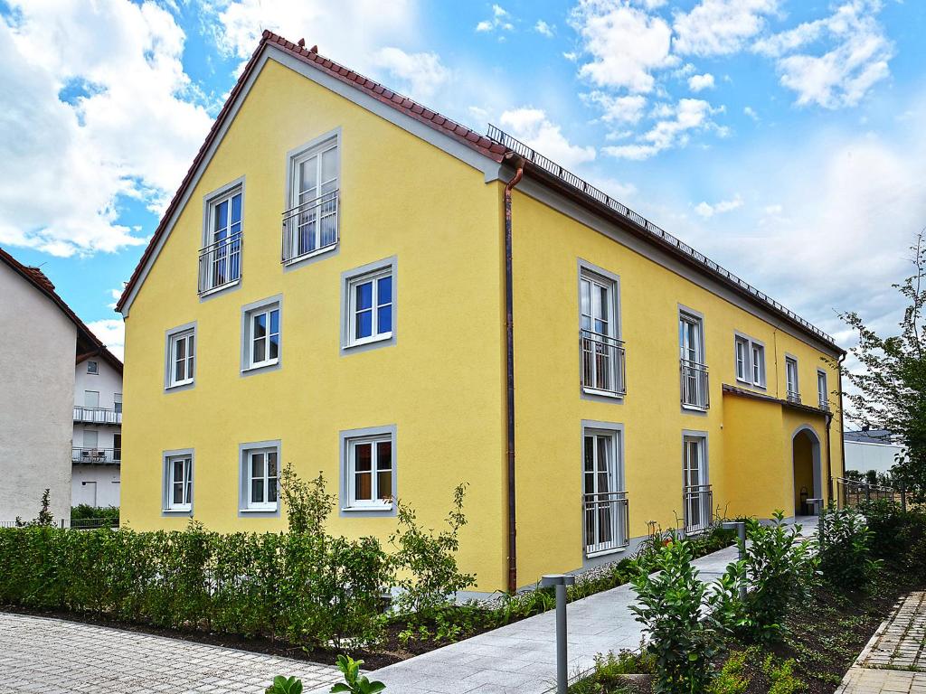 a yellow building with white windows on a street at Apparthotel Ampertal in Kranzberg