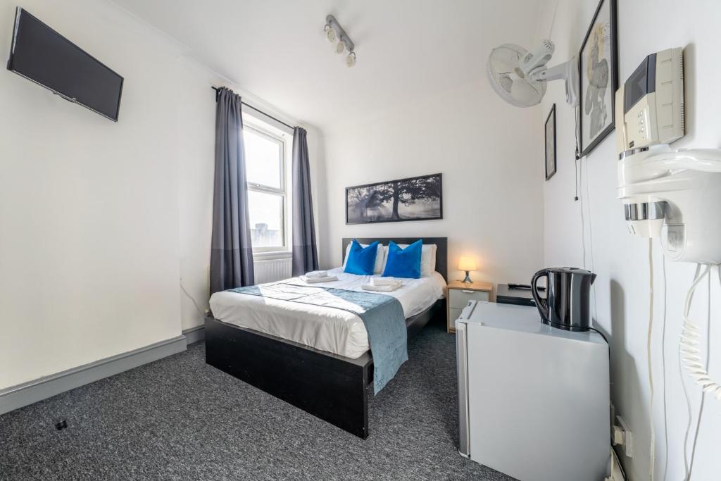 a bedroom with a bed with blue pillows and a window at Ryam Suites in London