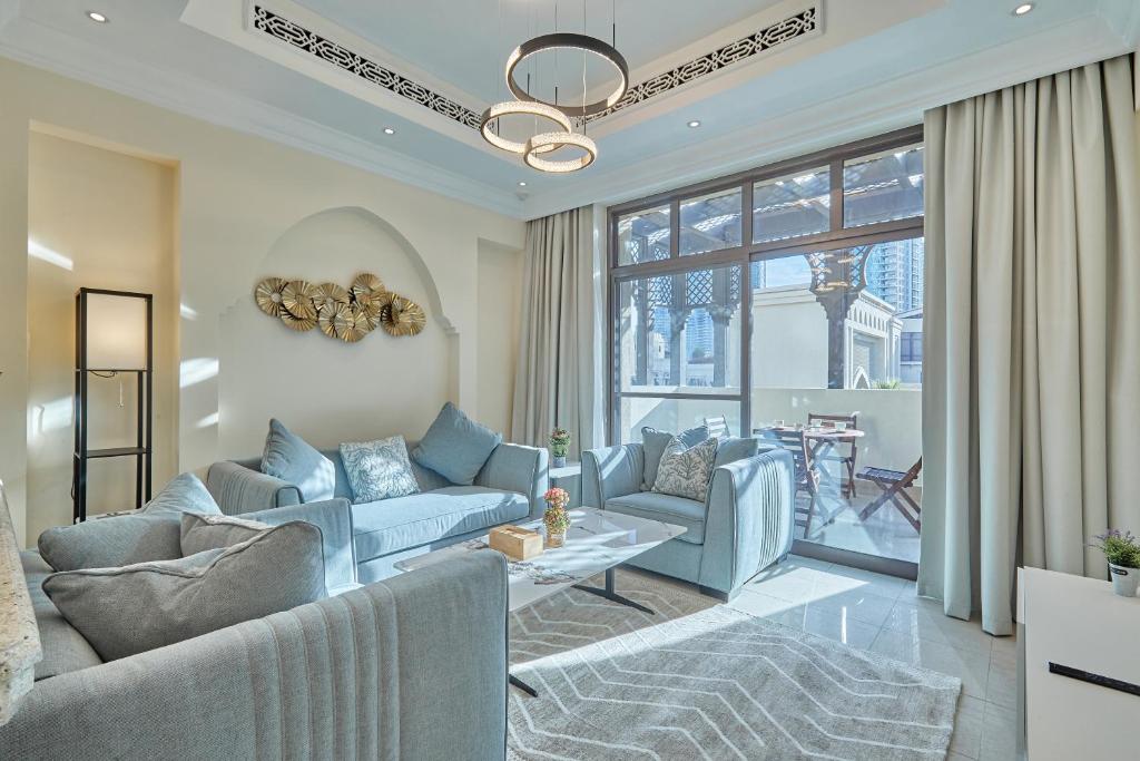 a living room with blue furniture and a large window at Burj khalifa view 1BR Souk al Bahar Tajer Residences Mint avenue Downtown Golden Homes in Dubai