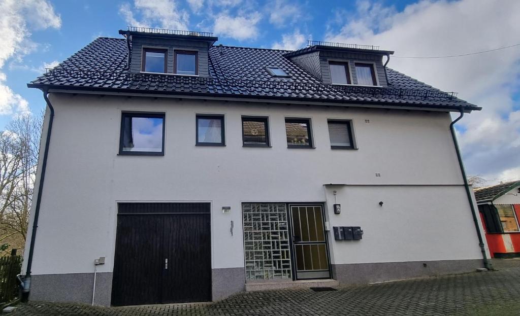 een wit huis met een zwarte deur bij Ferienwohnung Parkblick in Bad Berleburg