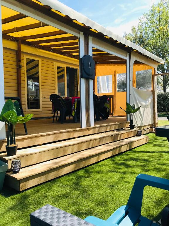 une maison dotée d'une terrasse avec des chaises sur l'herbe dans l'établissement Mobil-Home Camping 4* Landes Lac et Océan 6 à 8 p., à Gastes