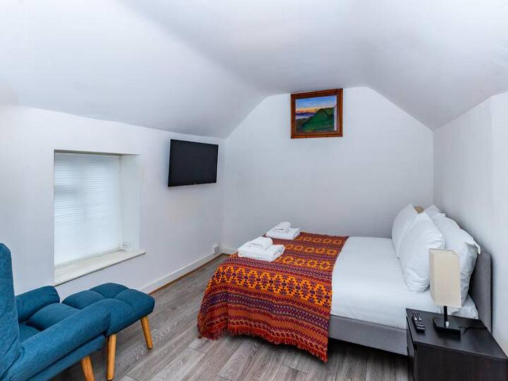 ein Schlafzimmer mit einem Bett und einem blauen Stuhl in der Unterkunft Pass the Keys Cosy Haven In Glastonbury: One Bedroom Apartment in Glastonbury