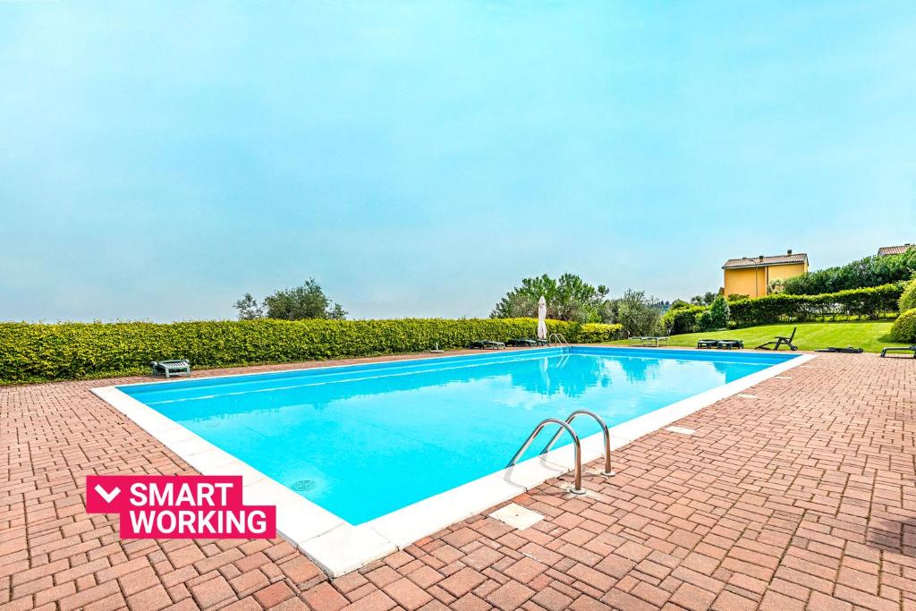 Una gran piscina con una pasarela de ladrillos a su alrededor. en Poggio Picedo P1-32 by Wonderful Italy, en Polpenazze del Garda