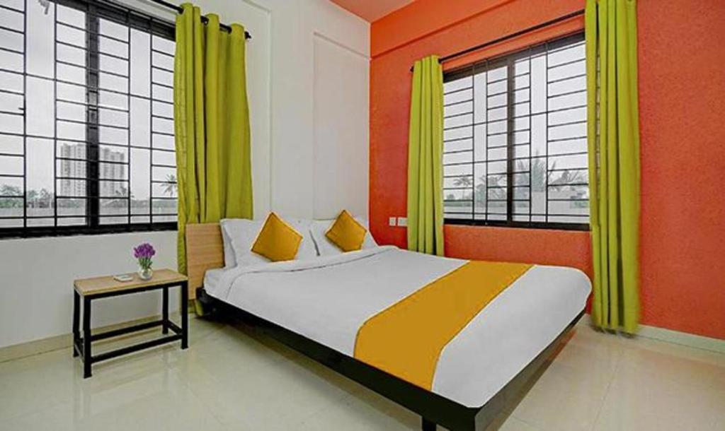 a bedroom with a bed with yellow and orange walls and windows at FabHotel The Paradise Inn Residency in Elūr