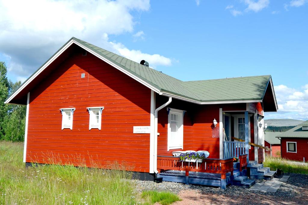een rood huis met een veranda in een veld bij Talo Ylläs in Äkäslompolo