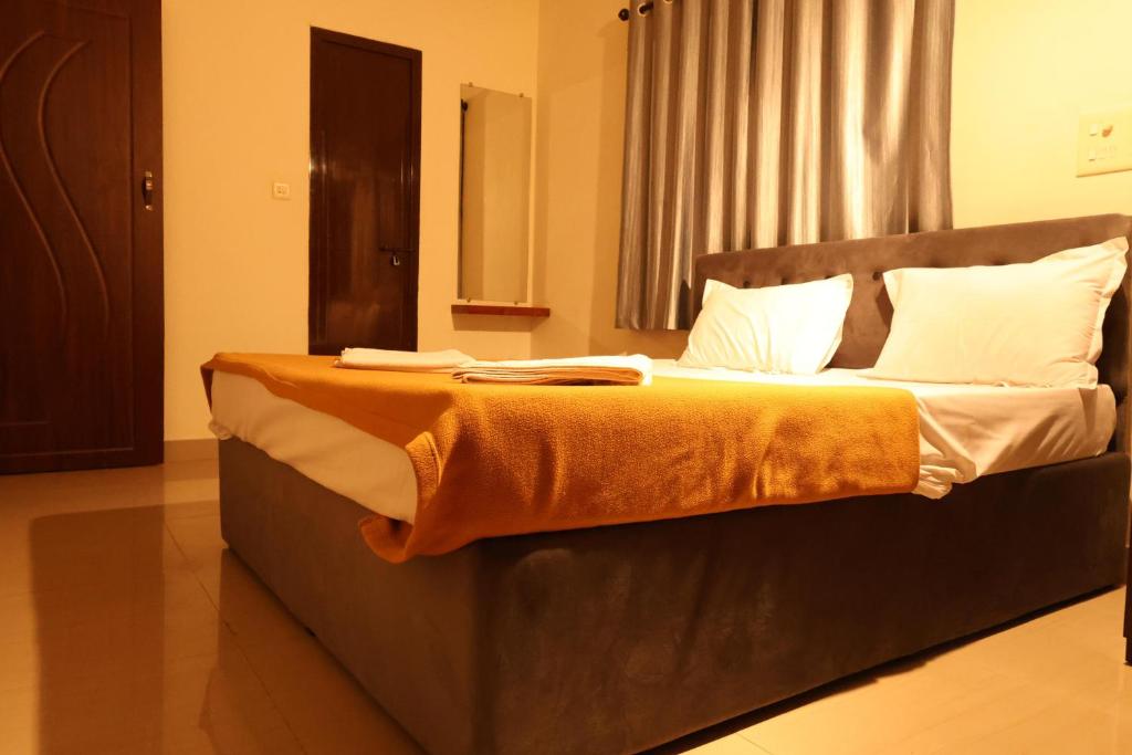 1 dormitorio con 1 cama grande con almohadas blancas en Hotel Aradhya Inn Deralakatte, en Mangalore
