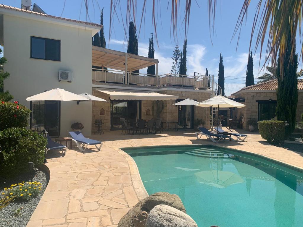 a swimming pool in front of a house with umbrellas at Villa Manzanillo in Coral Bay