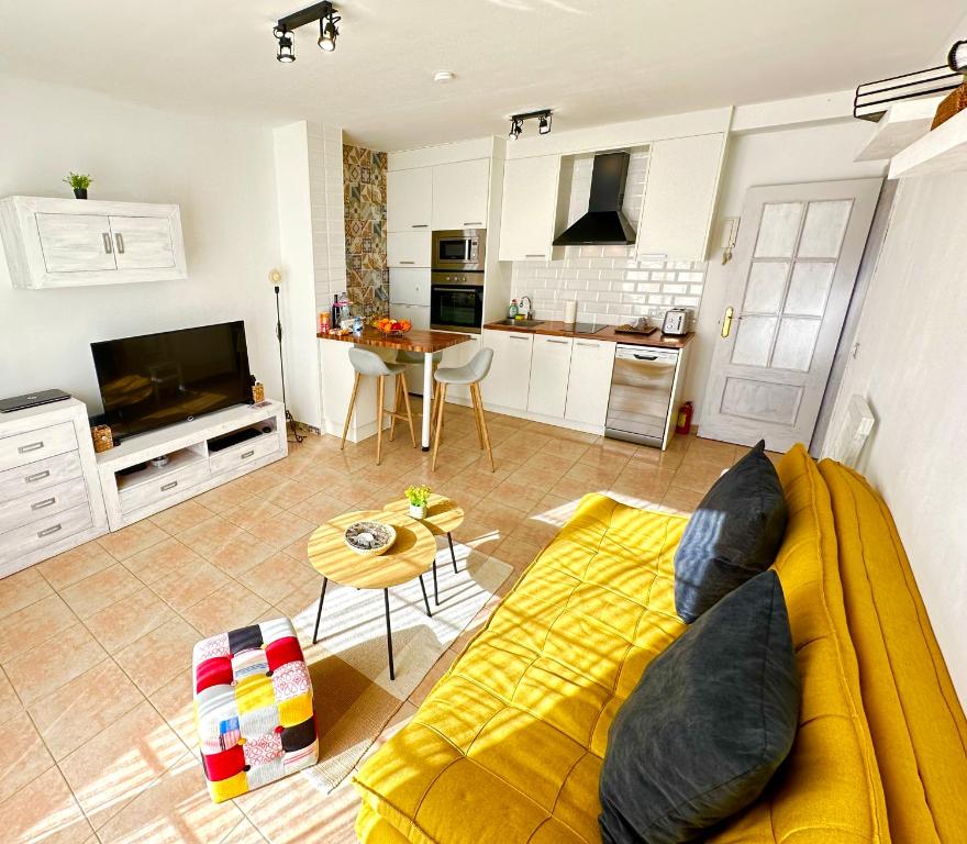 a living room with a yellow couch and a kitchen at Boutique Apartment Adeje I in Adeje