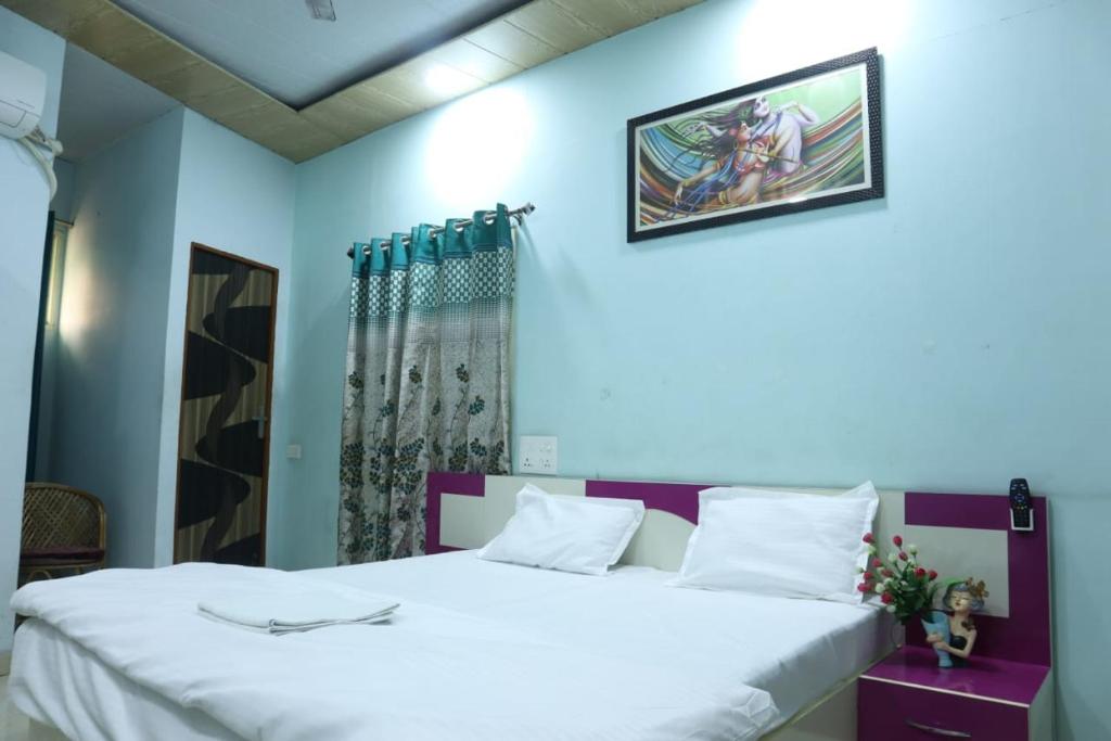een slaapkamer met een groot wit bed en blauwe muren bij Radhe Radhe Guest House in Dehradun