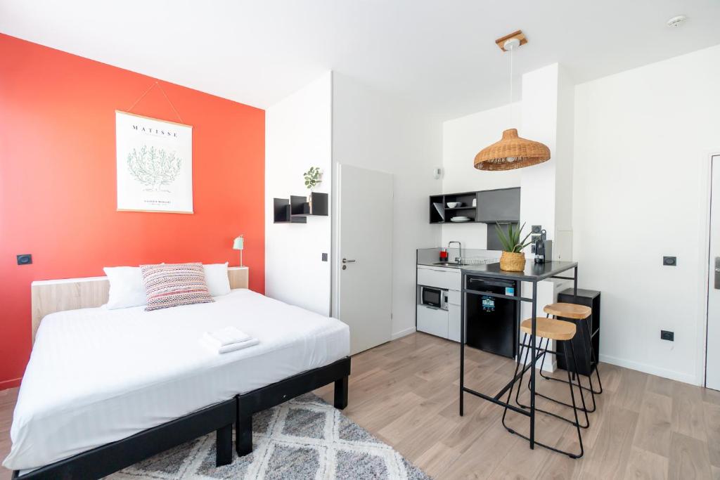 Un dormitorio con una pared de acento naranja y una cama en ECLA Paris Massy Palaiseau, en Palaiseau