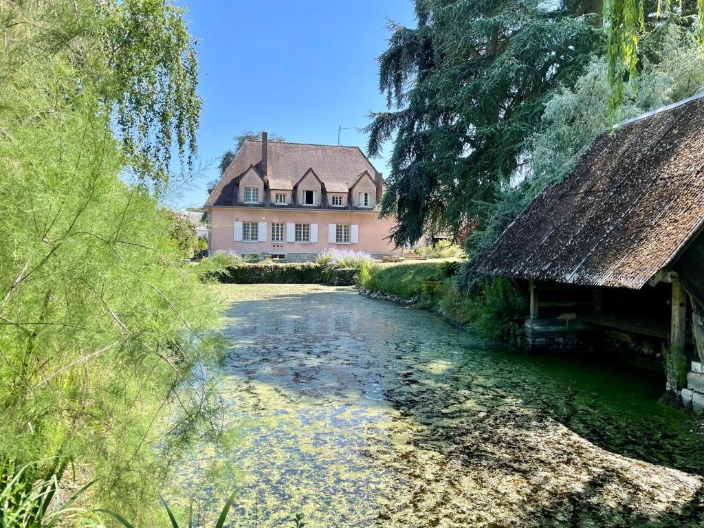 ein Haus und ein Fluss vor einem Haus in der Unterkunft La Meslaysienne - Comfortable house, swimming pool in Meslay-le-Vidame