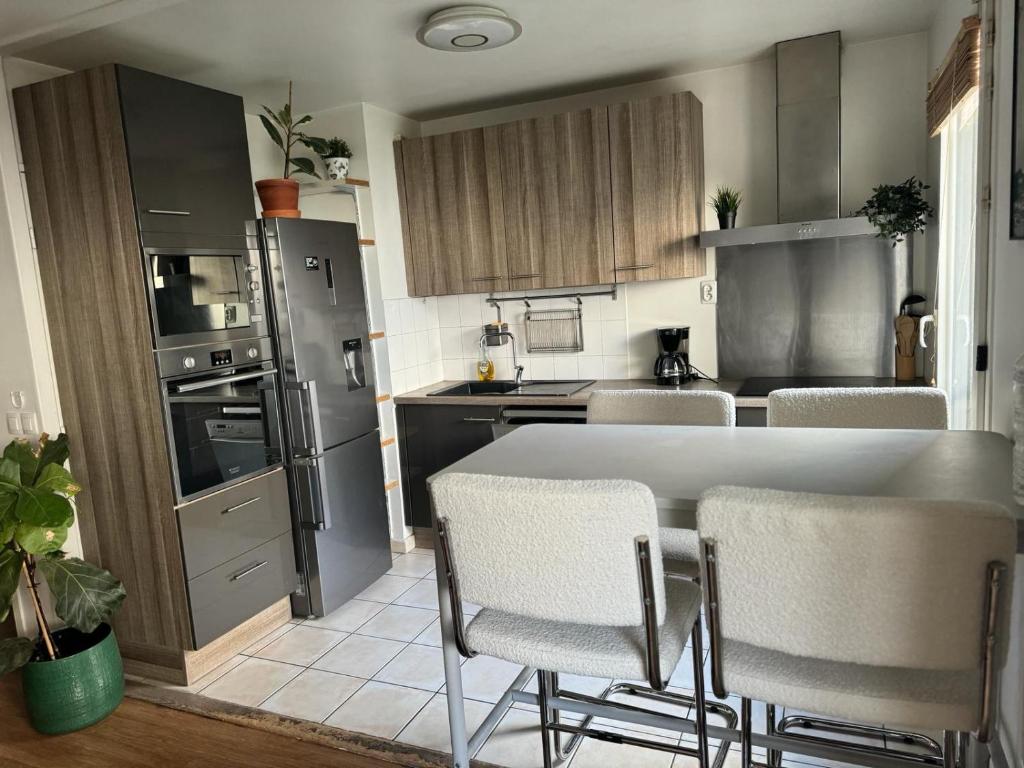 a kitchen with a table and chairs in a kitchen at Le cocon du stade de France in Saint-Denis