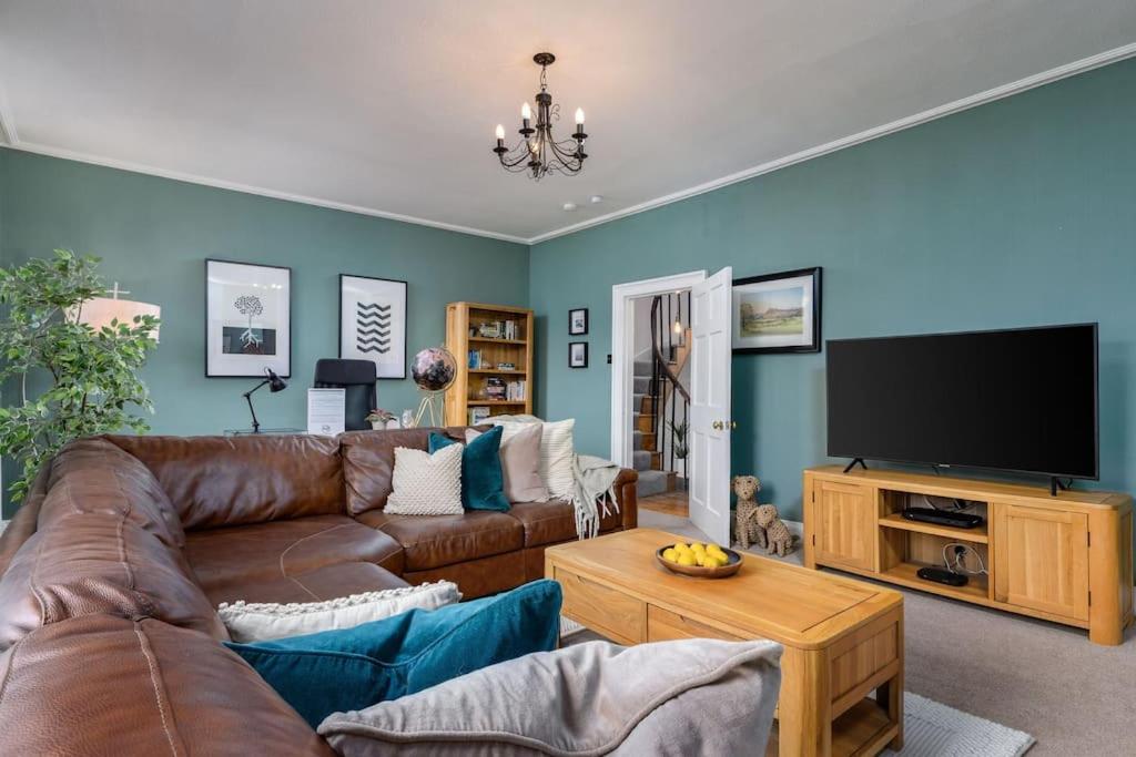 a living room with a couch and a flat screen tv at The Stirling Townhouse in Stirling