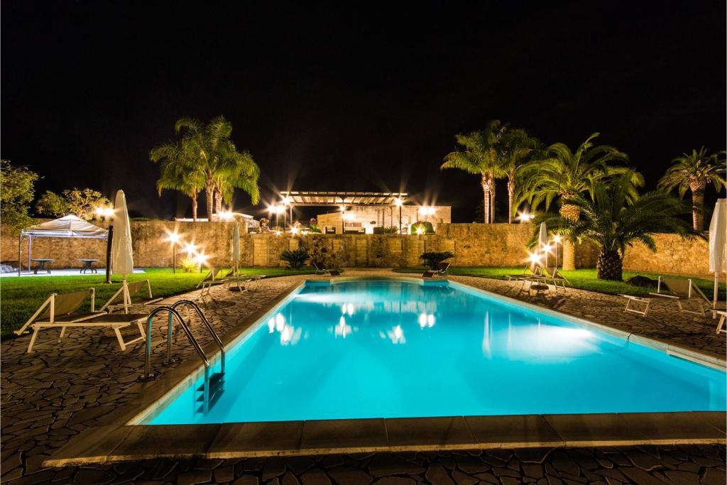 メレンドゥーニョにあるMasseria Relais Saraceno With Pool - Happy Rentalsの夜間のヤシの木があるスイミングプール