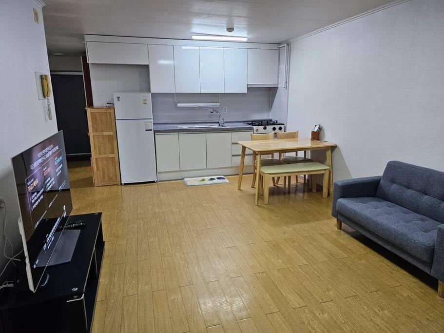 a living room with a couch and a table and a kitchen at BA Stay in Suwon