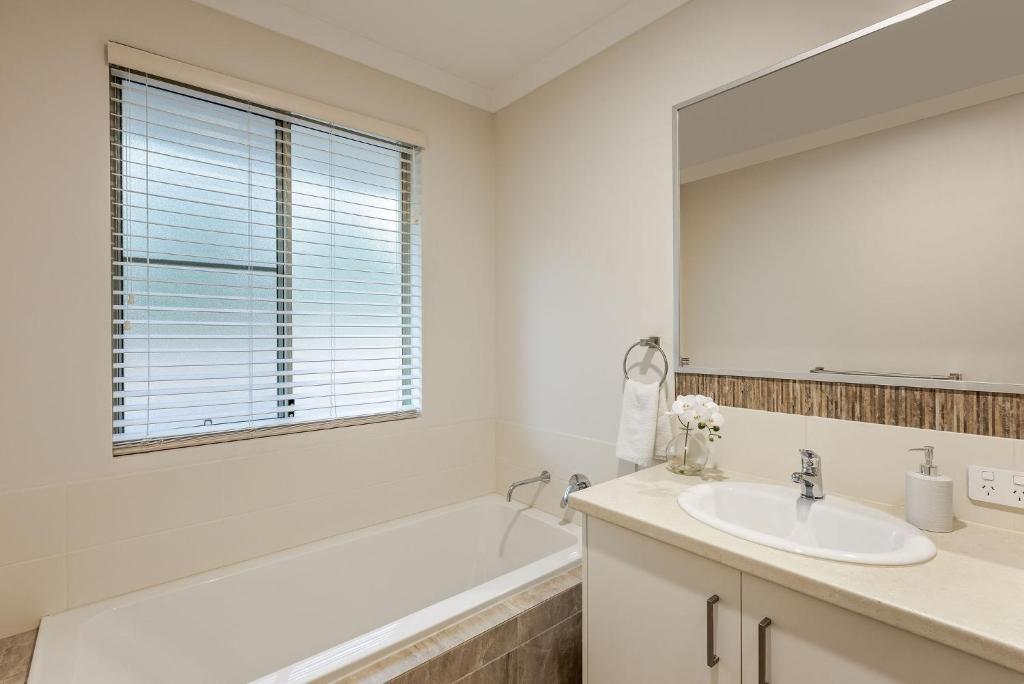 a bathroom with a tub and a sink and a mirror at Villa 16 @ Rivendell Winery Estate - Yallingup in Yallingup Siding